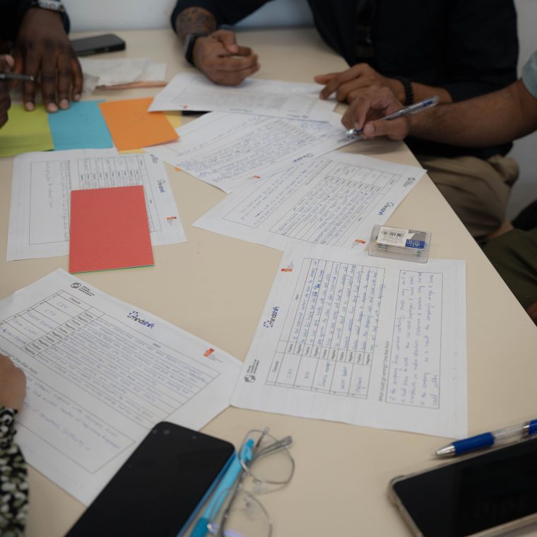 Une équipe diverse travaillant ensemble, examinant des documents et prenant des notes lors d'une réunion collaborative.
