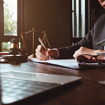 Avocat examinant et signant des documents juridiques sur un bureau.